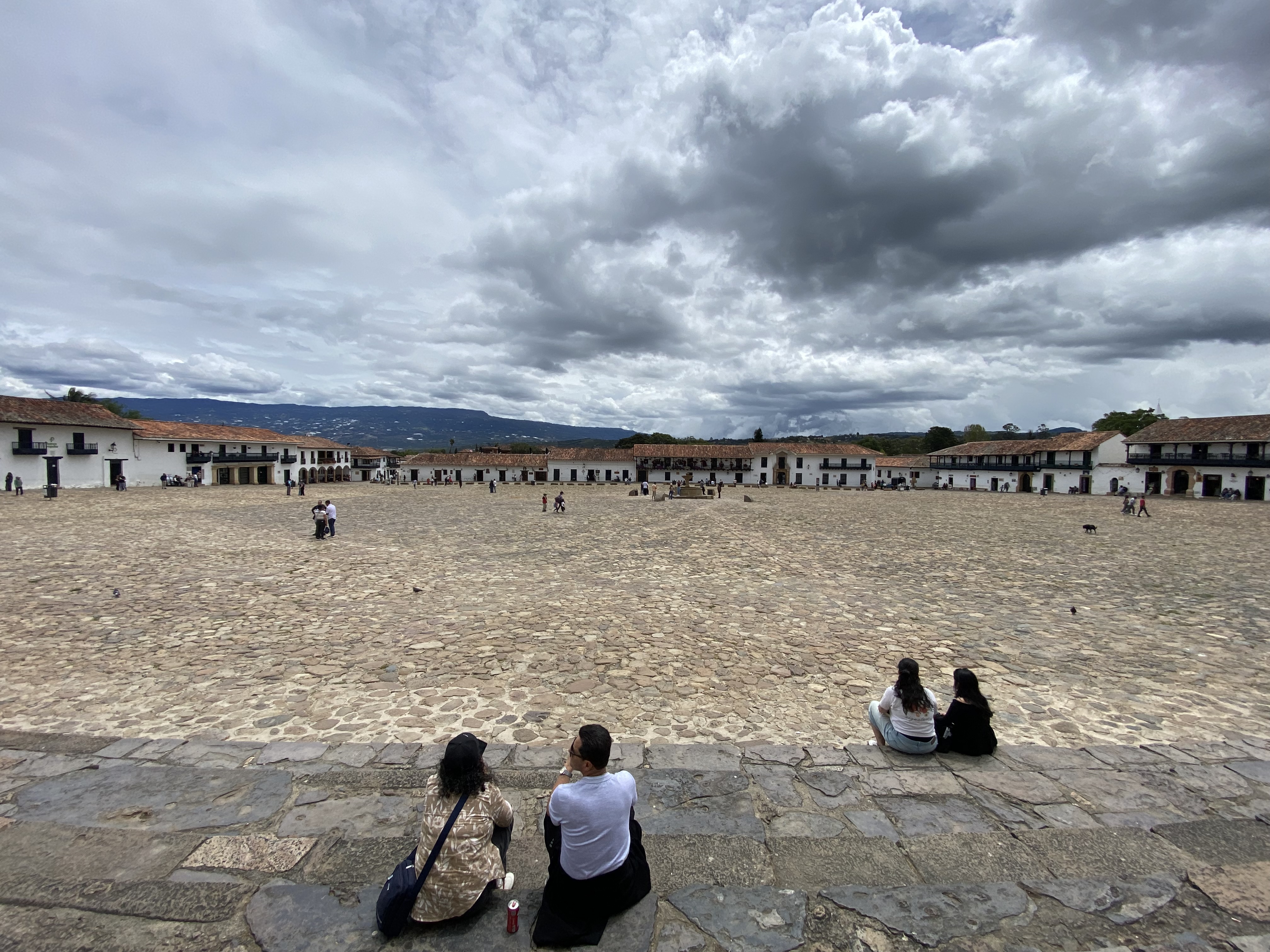 Vista panorámica de la Plaza Mayor de Villa de Leyva en Colombia con cielo nublado, suelo empedrado y arquitectura colonial española